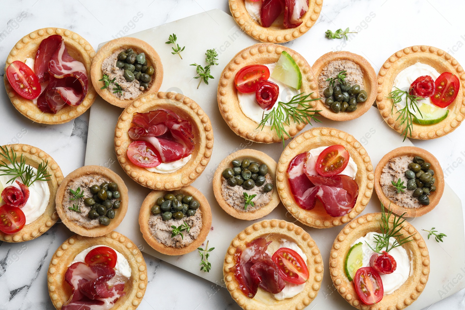 Photo of Different delicious canapes on white marble table, flat lay