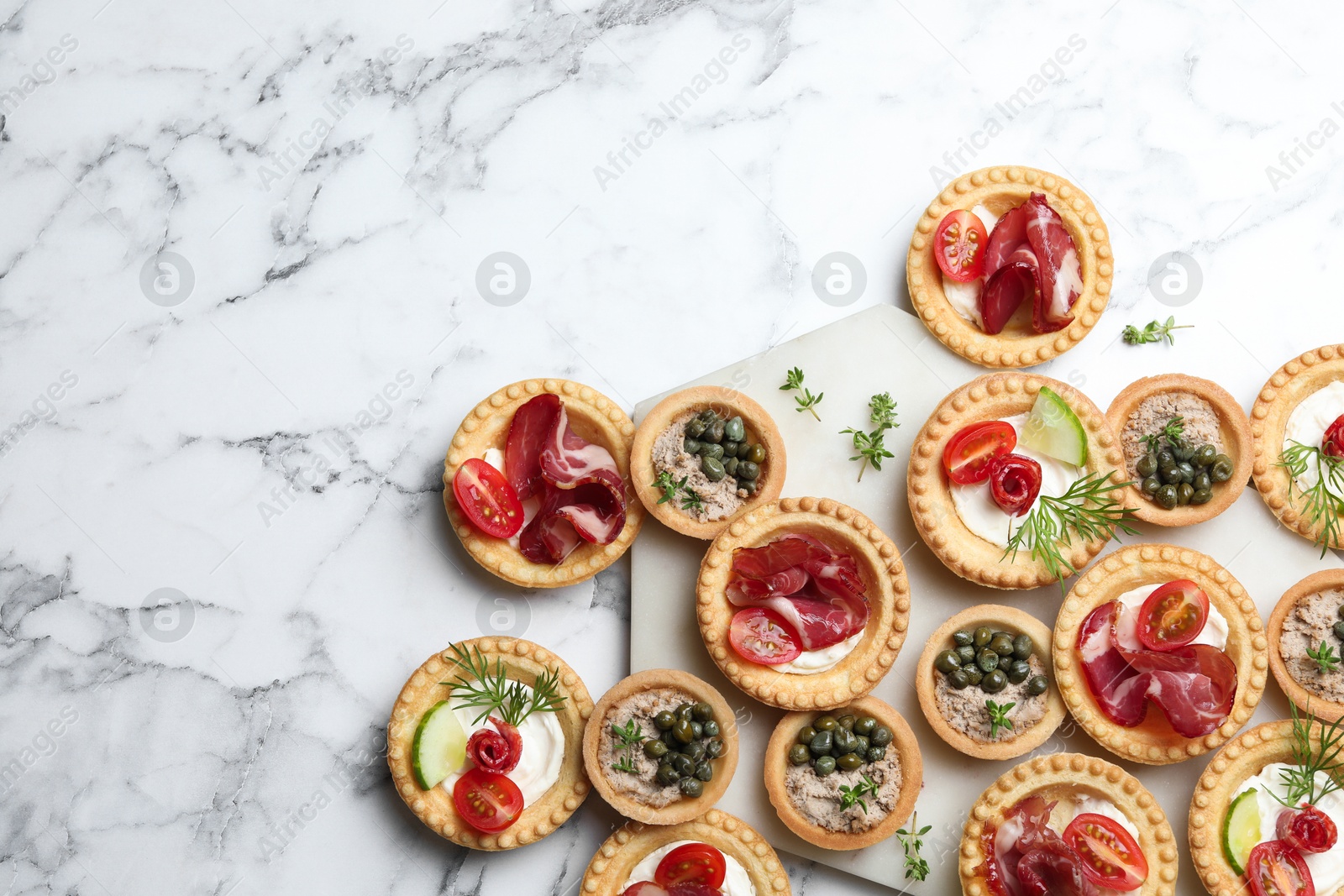 Photo of Different delicious canapes on white marble table, flat lay. Space for text