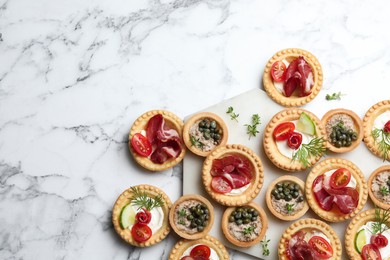 Different delicious canapes on white marble table, flat lay. Space for text