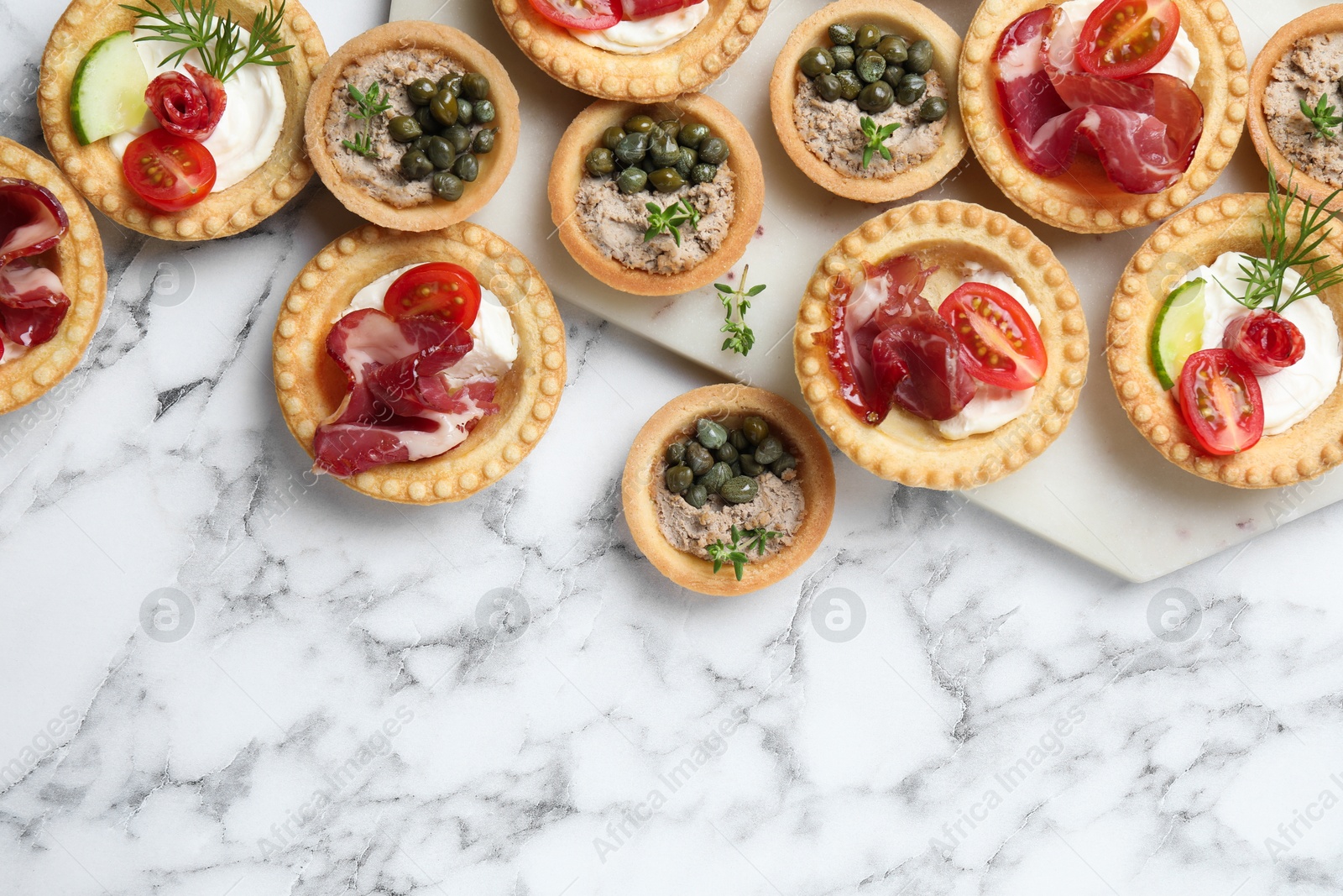 Photo of Different delicious canapes on white marble table, flat lay. Space for text