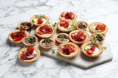 Photo of Different delicious canapes on white marble table