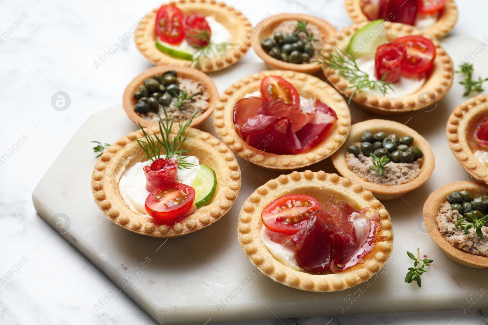 Photo of Different delicious canapes on white marble table