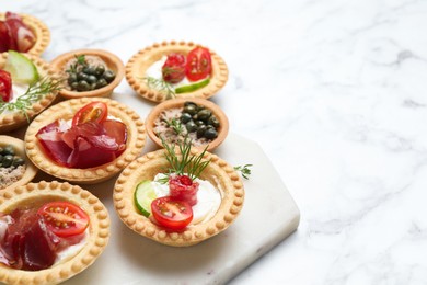 Photo of Different delicious canapes on white marble table, space for text