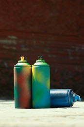 Photo of Many spray paint cans outdoors on sunny day