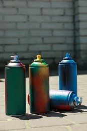 Photo of Many spray paint cans outdoors on sunny day