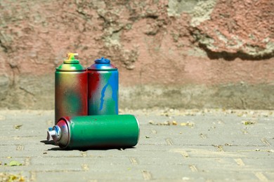 Photo of Many spray paint cans outdoors on sunny day, space for text