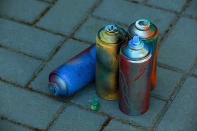 Many spray paint cans on pavement outdoors