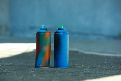 Many spray paint cans on ground outdoors