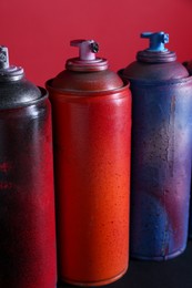 Many spray paint cans on color background, closeup