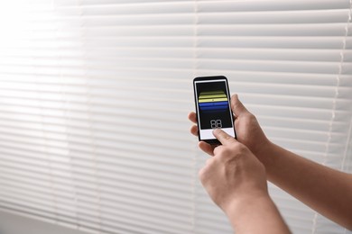 Photo of Man using phone to adjust window blinds indoors, closeup. Space for text