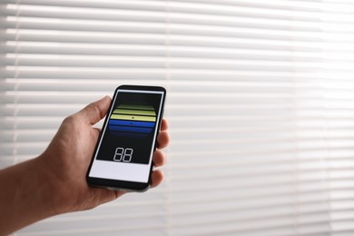 Photo of Man using phone to adjust window blinds indoors, closeup. Space for text