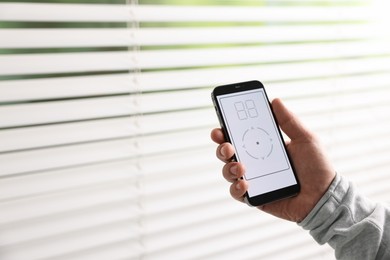 Photo of Man using phone to adjust window blinds indoors, closeup. Space for text