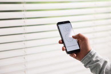 Photo of Man using phone to adjust window blinds indoors, closeup. Space for text