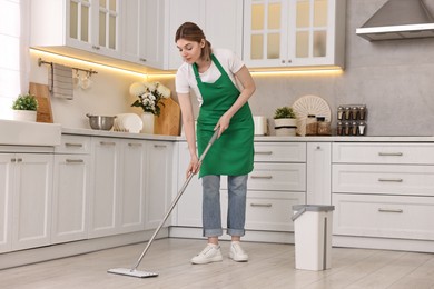 Photo of Cleaning service worker washing floor with mop in kitchen