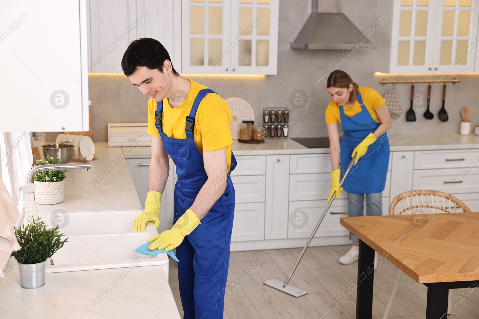 Photo of Professional janitors working in kitchen. Cleaning service