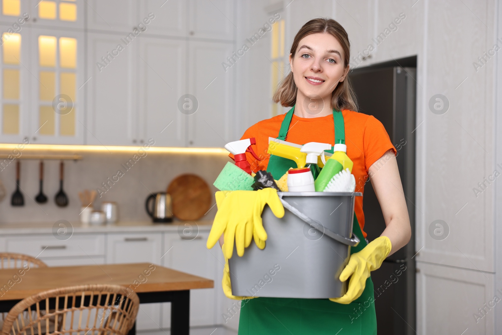 Photo of Cleaning service worker holding bucket with supplies in kitchen