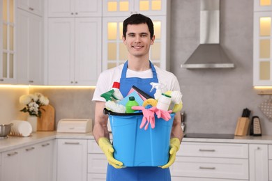 Cleaning service worker holding bucket with supplies in kitchen