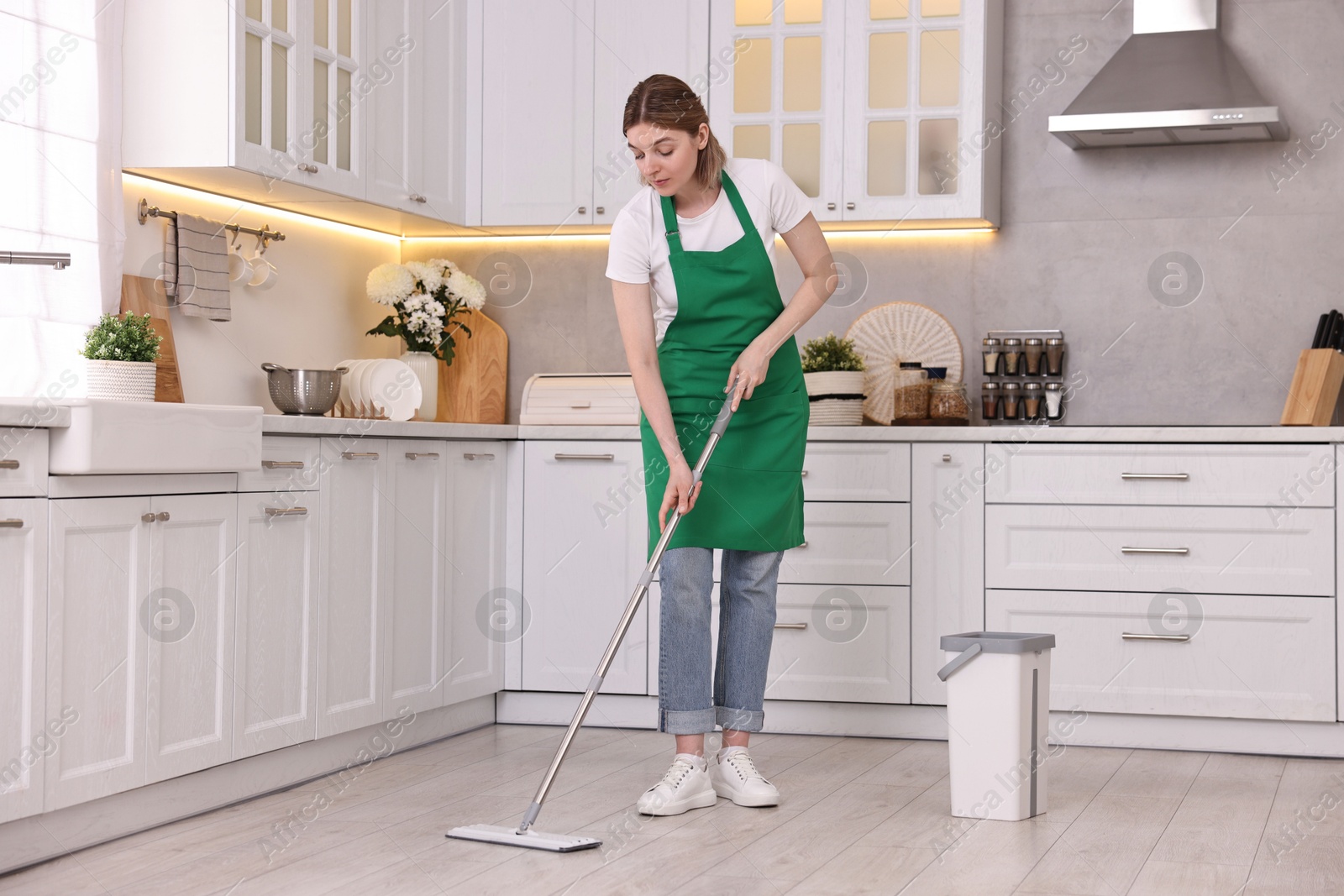 Photo of Cleaning service worker washing floor with mop in kitchen