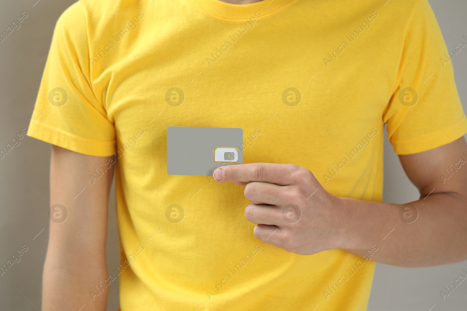 Photo of Man holding SIM card on grey background, closeup