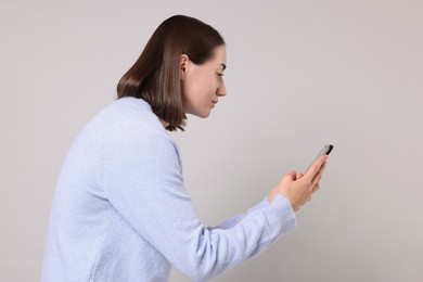 Photo of Woman with poor posture using smartphone on gray background