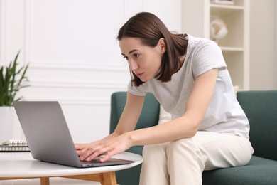 Woman with poor posture using laptop at home