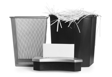 Shredder, metal basket and paper strips on white background