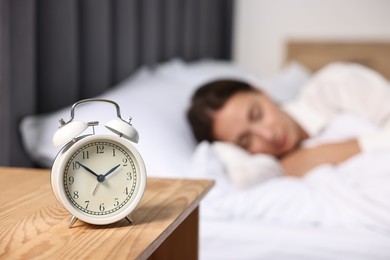 Woman sleeping in bed at lunch time, focus on alarm clock