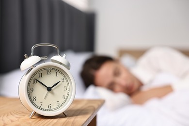 Woman sleeping in bed at lunch time, focus on alarm clock