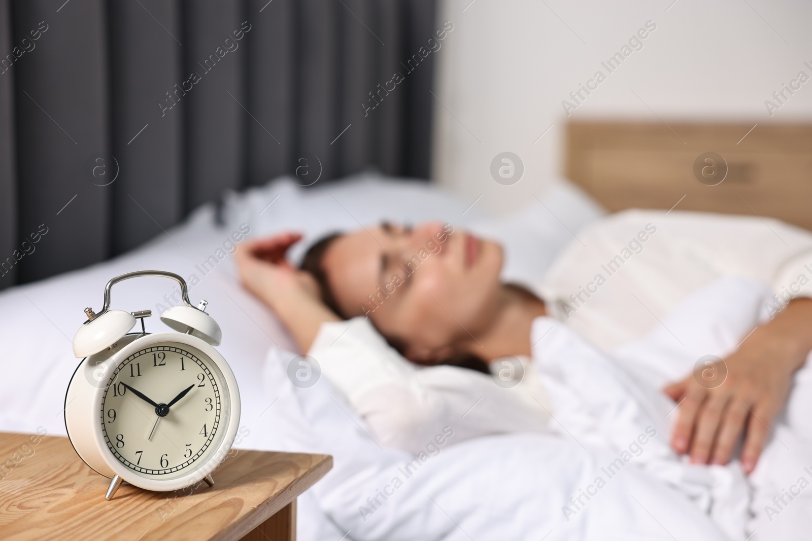 Photo of Woman sleeping in bed at lunch time, focus on alarm clock