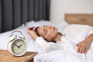Photo of Woman sleeping in bed at lunch time, focus on alarm clock