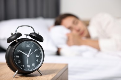 Woman sleeping in bed at lunch time, focus on alarm clock