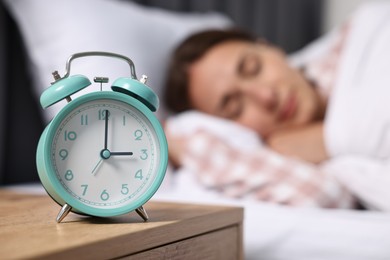 Woman sleeping in bed at lunch time, focus on alarm clock