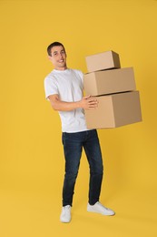 Moving into new house. Man with cardboard boxes on yellow background