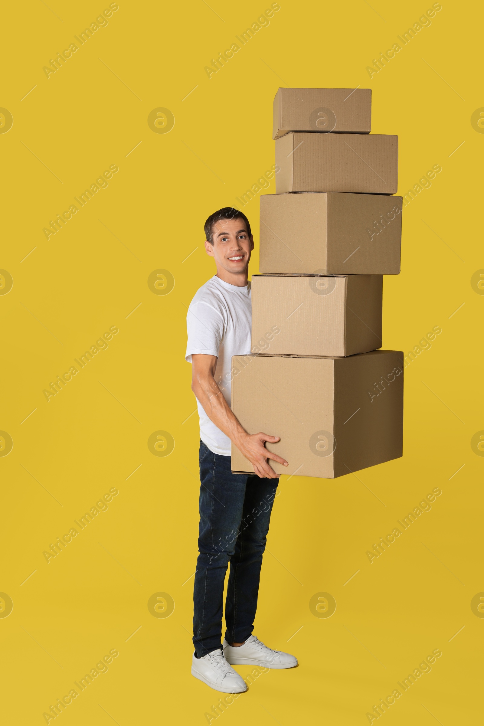 Photo of Moving into new house. Man with cardboard boxes on yellow background