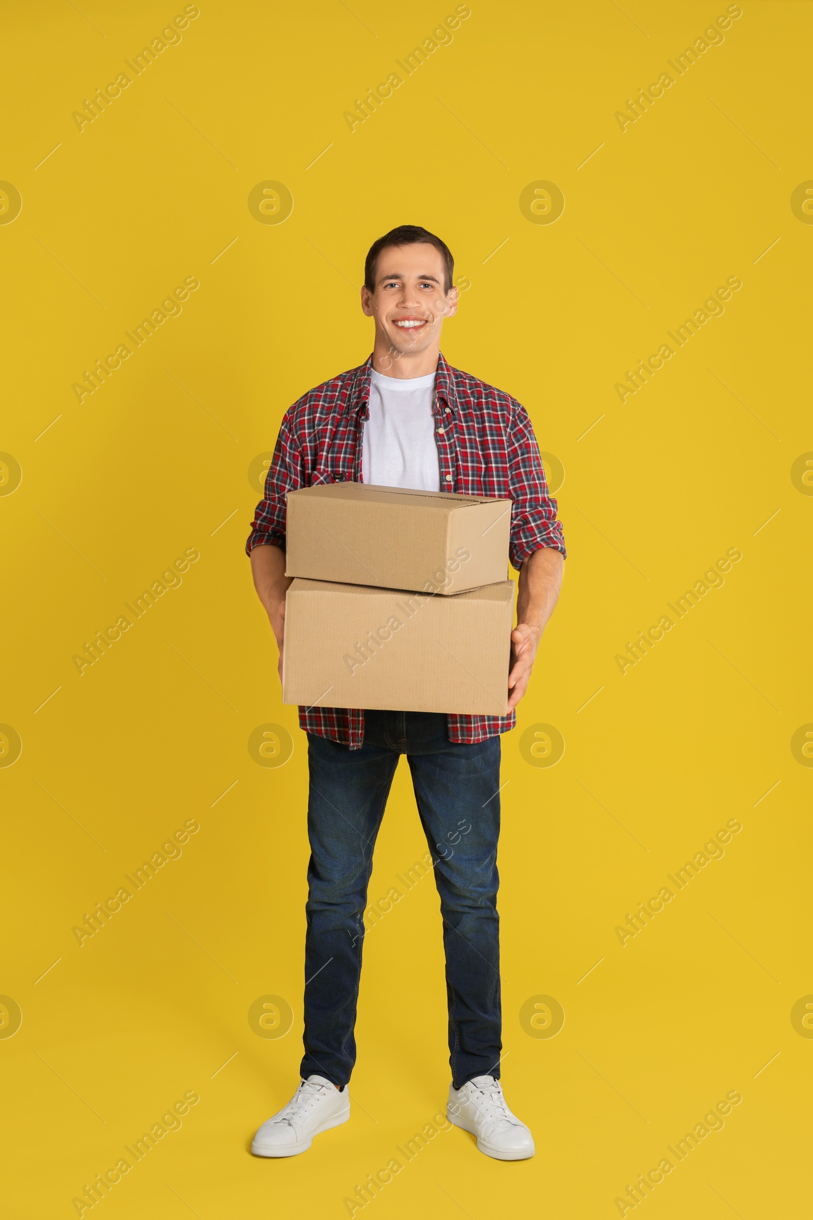 Photo of Moving into new house. Man with cardboard boxes on yellow background