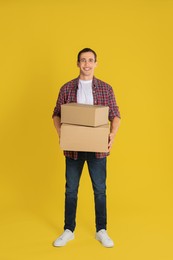 Photo of Moving into new house. Man with cardboard boxes on yellow background