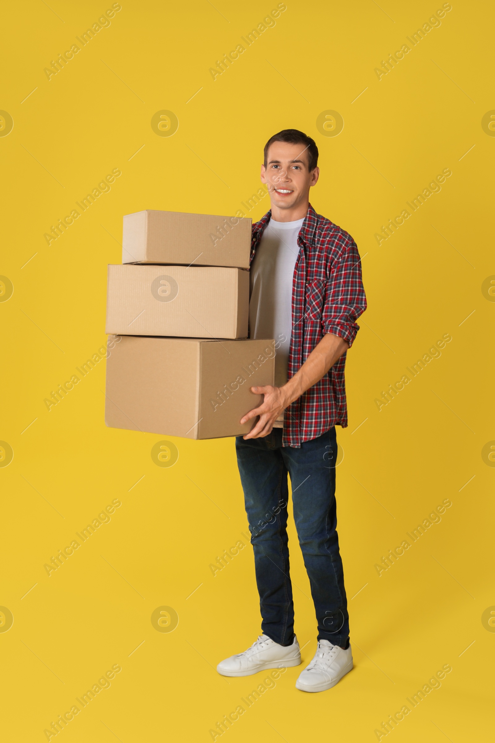 Photo of Moving into new house. Man with cardboard boxes on yellow background