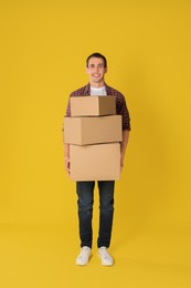 Photo of Moving into new house. Man with cardboard boxes on yellow background