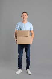 Photo of Moving into new house. Man with cardboard boxes on grey background