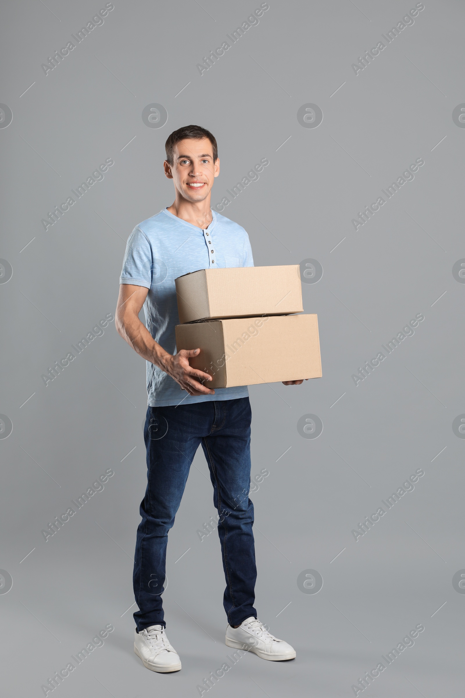 Photo of Moving into new house. Man with cardboard boxes on grey background