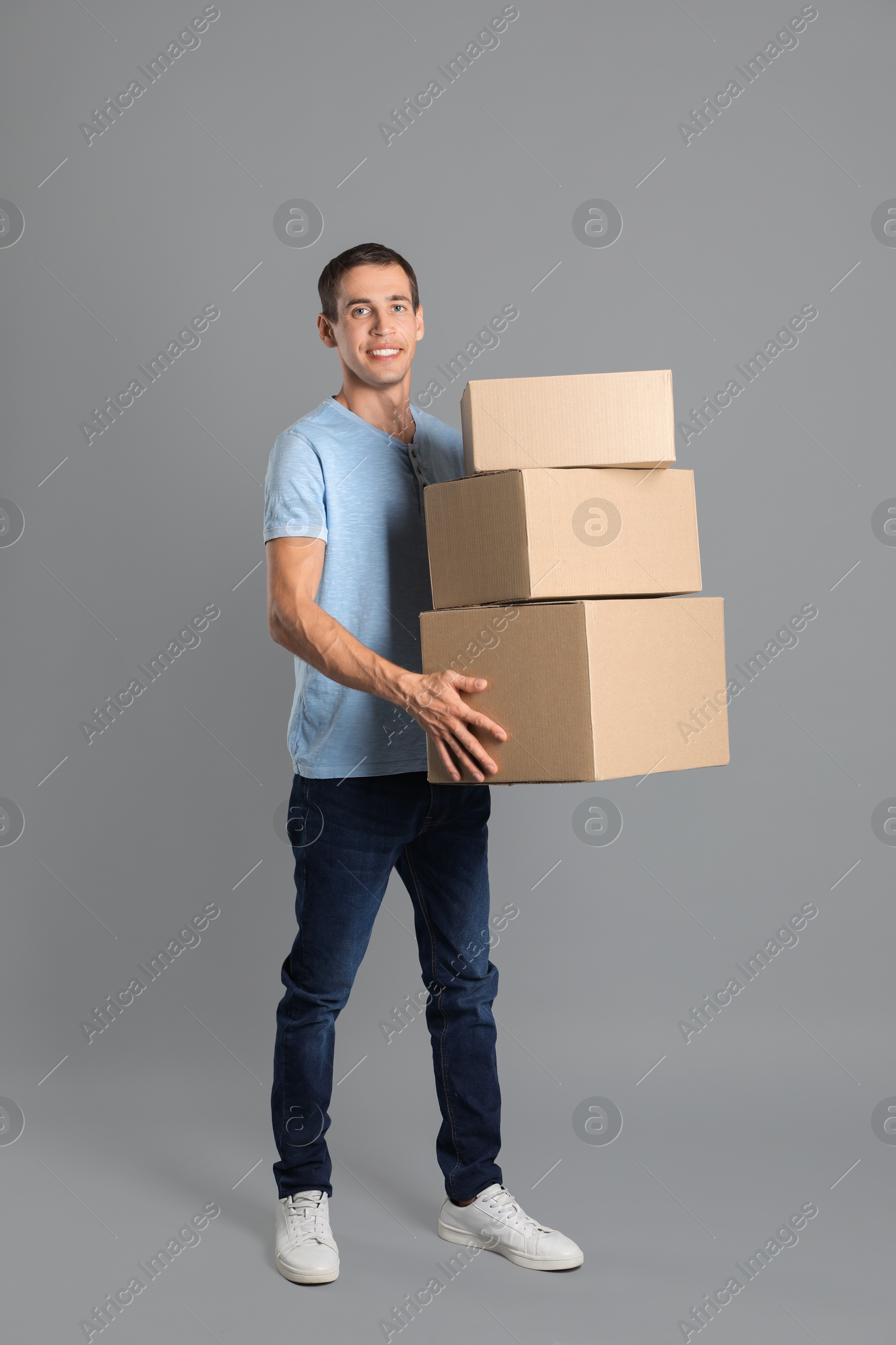 Photo of Moving into new house. Man with cardboard boxes on grey background