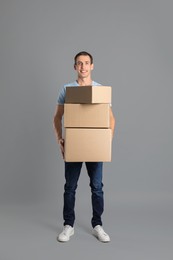 Photo of Moving into new house. Man with cardboard boxes on grey background