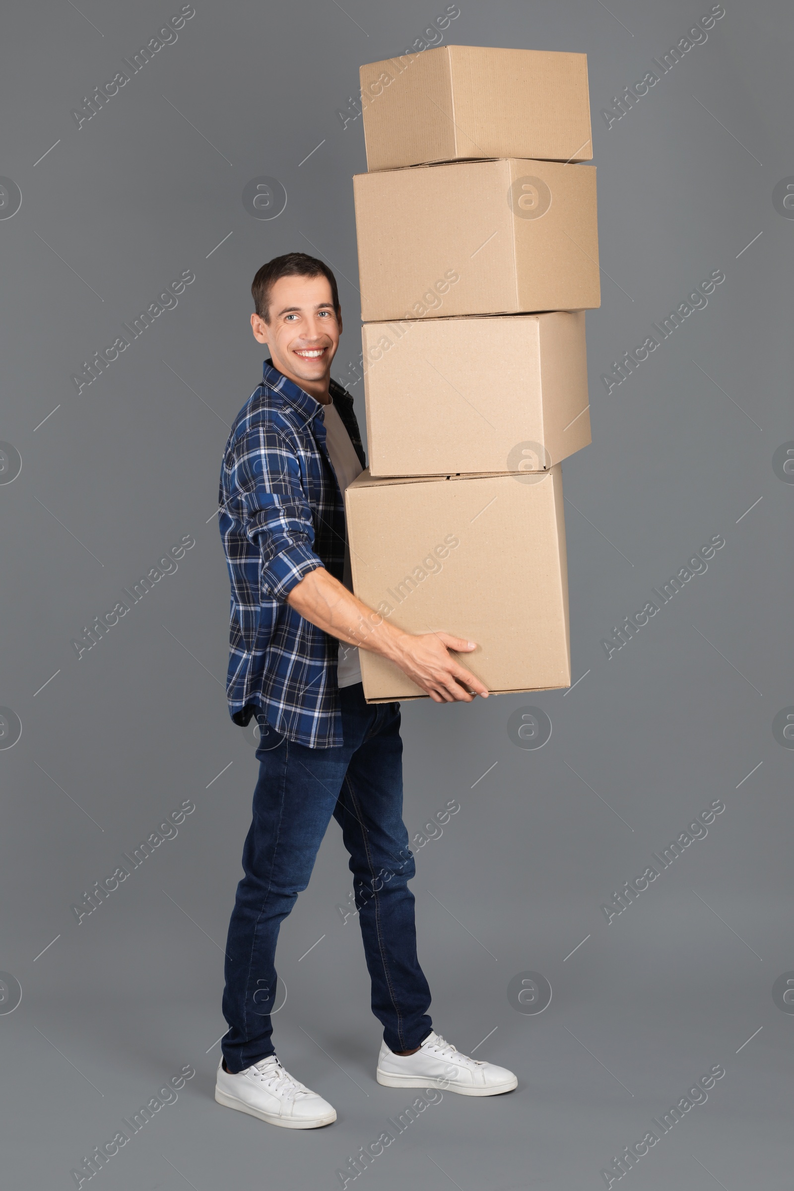 Photo of Moving into new house. Man with cardboard boxes on grey background