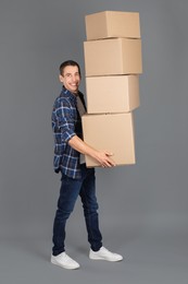Photo of Moving into new house. Man with cardboard boxes on grey background