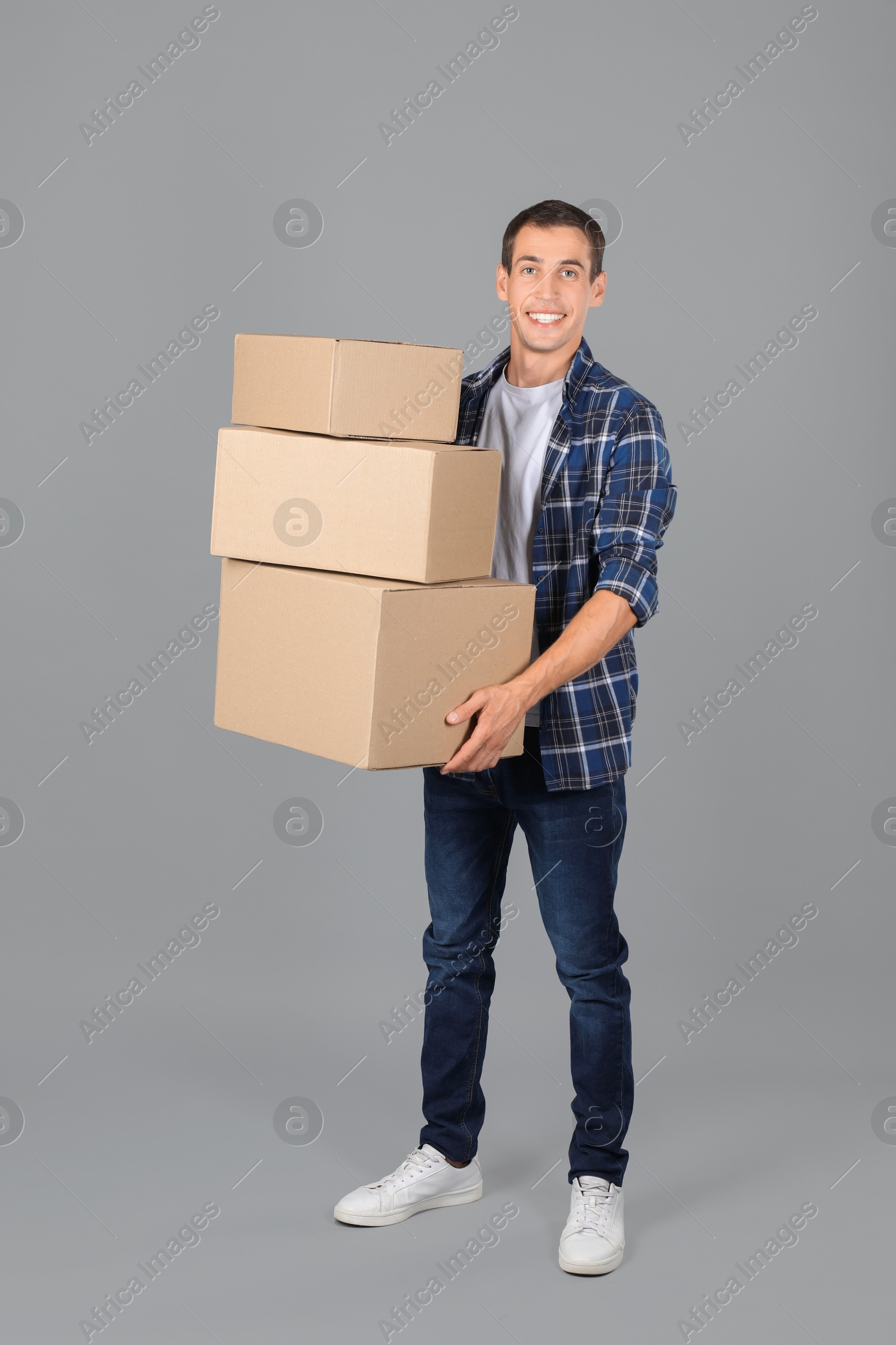 Photo of Moving into new house. Man with cardboard boxes on grey background