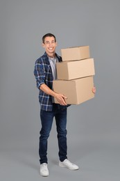 Photo of Moving into new house. Man with cardboard boxes on grey background