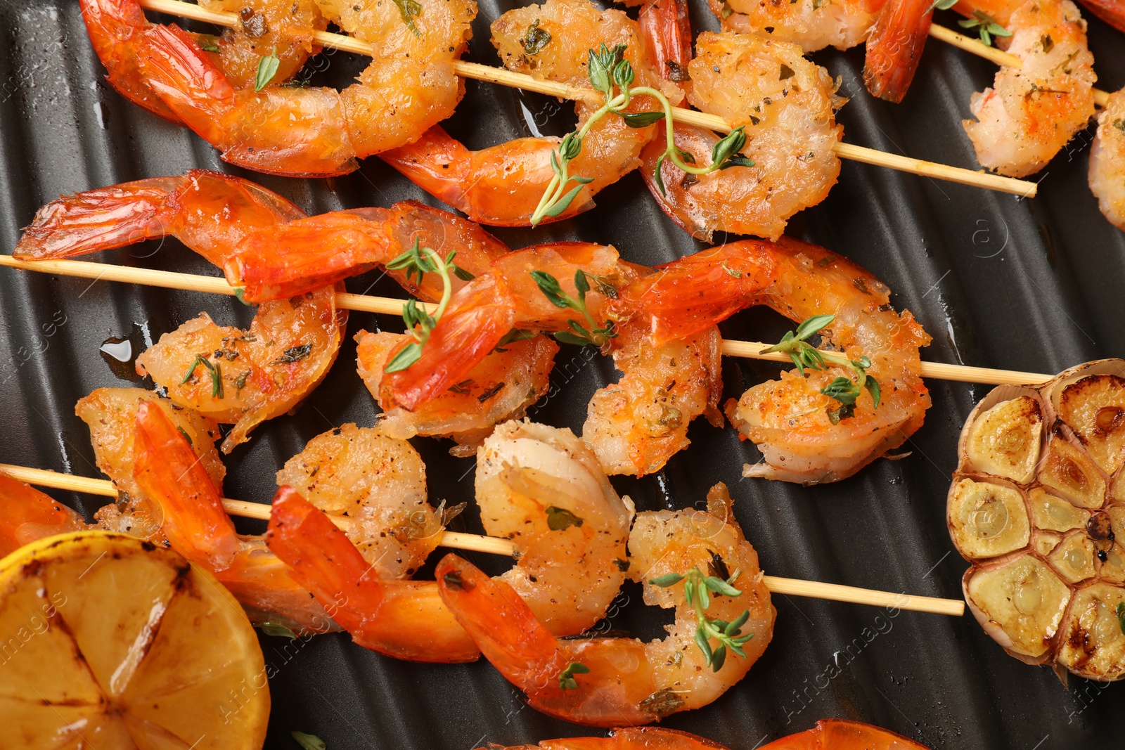 Photo of Skewers with delicious shrimps on grill pan, top view