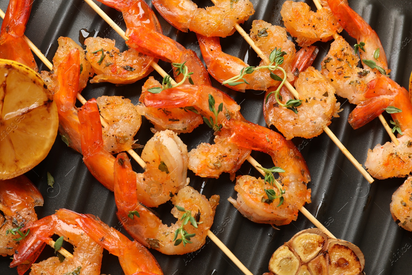 Photo of Skewers with delicious shrimps on grill pan, top view