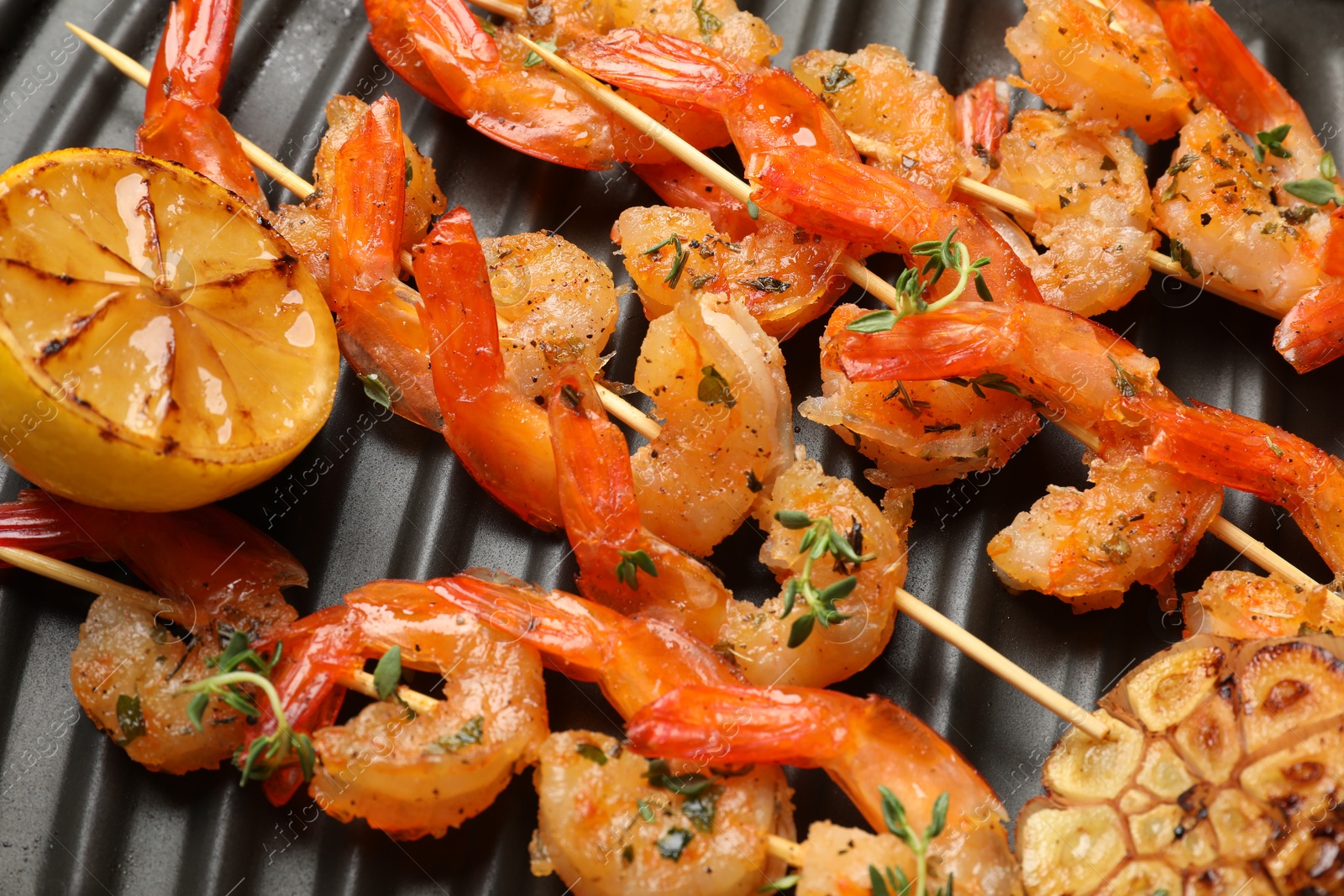 Photo of Skewers with delicious shrimps on grill pan, top view