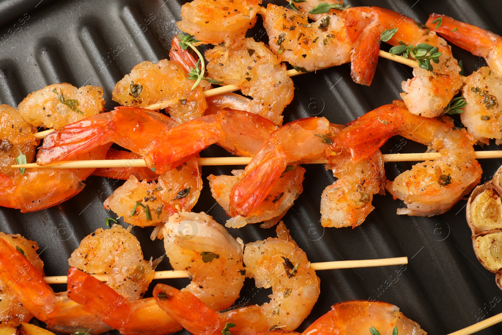 Photo of Skewers with delicious shrimps on grill pan, top view